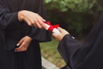 Closeup of hands giving graduation certificate