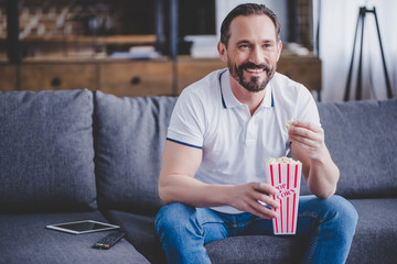 man watching tv and eating popcorn