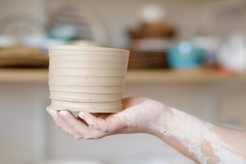 pottery workshop. artisan hand showing a craft clay jug. handmade crockery concept