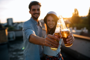 Young happy couple toasting with beer outdoors