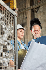 Zwei Metallarbeiter schauen auf Bauplan