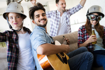 Cheerful friends having party together and playing instruments