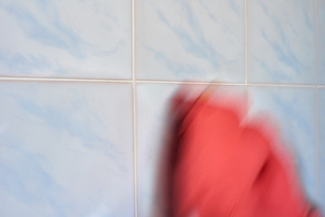 Blurred image of hand in protective glove doing disinfection, natural motion blur