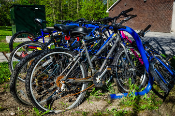 Fototapeta na wymiar Right side view of crowded blue bike rack with deserted biycycles