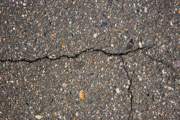 the crack on the asphalt surface with lots of stones