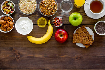 Set of products for healthy vegetarian breakfast. Fruits, oatmeal, yogurt, nuts, crispbreads, chia on dark wooden background top view space for text