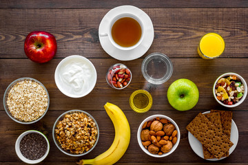 Set of products for healthy vegetarian breakfast. Fruits, oatmeal, yogurt, nuts, crispbreads, chia on dark wooden background top view
