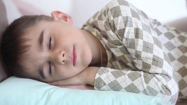 Mom kisses the little son while he is sleeping. The son wakes up having a good mood