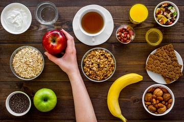 Set of products for healthy vegetarian breakfast. Fruits, oatmeal, yogurt, nuts, crispbreads, chia on dark wooden background top view/ Yand takes apple
