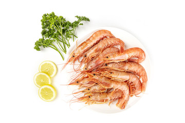 Overhead photo of plate of raw shrimps on white, with parsley and lemon, with copy space