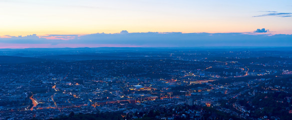 Night falls over Stuttgart City in Germany / Turning on the lights in the city