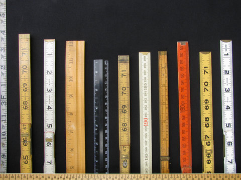 Folding rulers and scales in metric and inches form a bar chart and represent concepts of accuracy, measurement and accuracy.