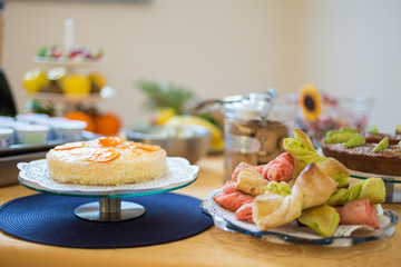 Blurred sweet breakfast, self service. Orange cake and colorful puff pastries 