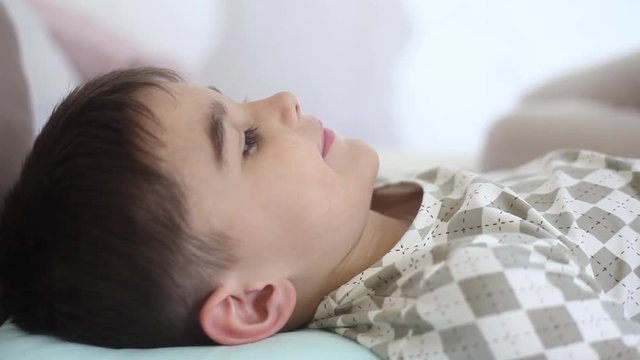 A beautiful girl kisses a young child who lies on a bed