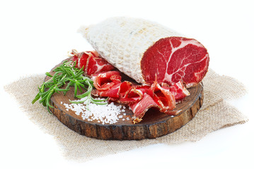 Sliced cured coppa with a sprig of rosemary.