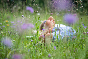 Junges Mädchen liegt entspannt in Blumenwiese, Füße