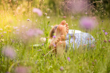 Junges Mädchen liegt entspannt in Blumenwiese, Füße - obrazy, fototapety, plakaty