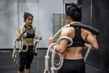 Young Asian gymnast woman carrying ropes on shoulders for gymnastic exercise in fitness gym