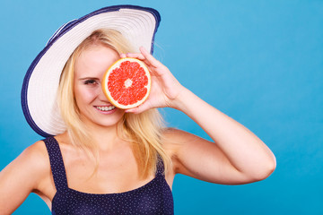 Woman holding red grapefruit fruit wearin sun hat
