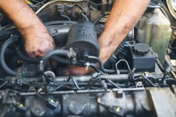 Close-up of mechanic repairing an engine. Man hands in oil