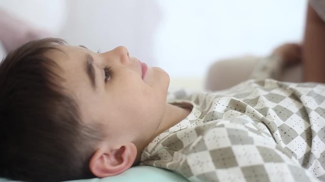 A beautiful girl kisses a small child with short hair while he is sleeping. slow motion