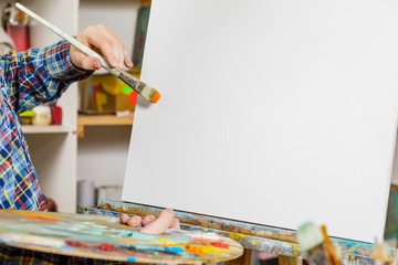 the hand of a man with a brush on the canvas. art, creativity, hobby and people