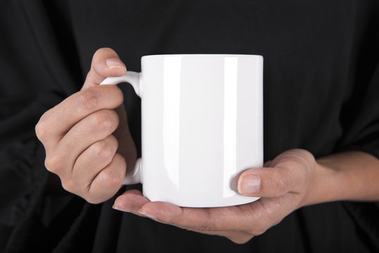Hand Holding White coffee cup. mock up for creative design branding.