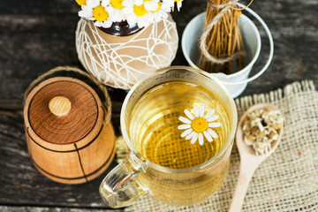 Fototapeta na wymiar cup of herbal chamomile tea with fresh daisy flowers on wooden background. doctor treatment and prevention of immune concept, medicine - folk, alternative, complementary, traditional medicine 