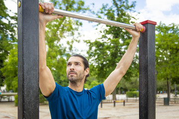 Obraz premium Young man making Pull-up strength training exercise