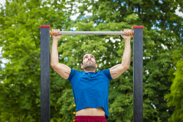 Fototapeta premium Young man making Pull-up strength training exercise