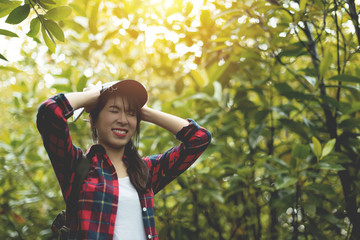 Stressed Asian girl traveler in red plaid shirt holding her head with her hands.