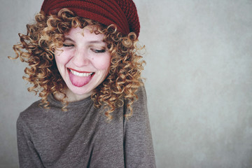 Preciosa y divertida mujer rubia con el pelo rizado que sonríe para la foto
