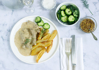 Beef Stroganoff traditional Russian dish of beef in sauce, served with fried potatoes, canned cucumbers, vodka.