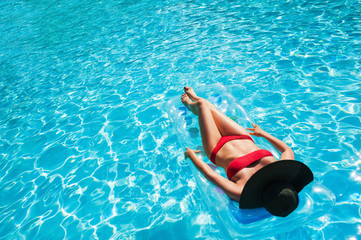 Woman relaxing on the inflatable mattress in swimming pool.