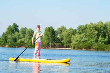Adult woman is floating on a SUP board