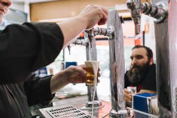 Bearded man who drinks beer in a bar in Madrid city