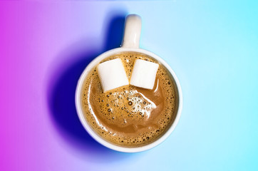 a mug of hot coffee with marshmallows. marshmallow like eyes. smile in the coffee. turquoise background