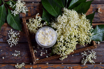 Elderflower sugar and blossom flower in wooden background. Edible elderberry flowers add flavour and aroma to drink and dessert. Sambucus nigra. Copy space