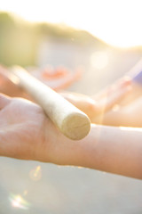 Blurred hands hold a blurred, wooden stick. teambuilding activity with a stick and hands. colleagues. rays of the sun fall, light up your hands and stick, show the way