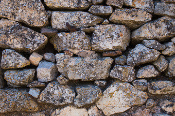 Texture of an ancient stone on a wall covered with moss