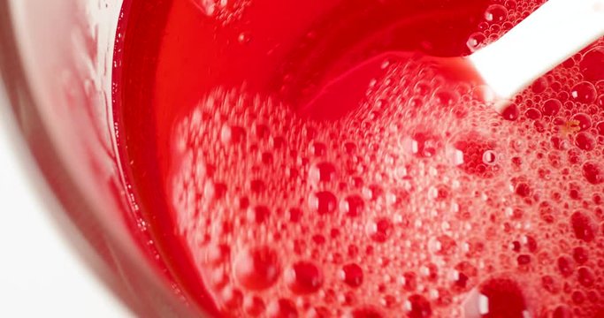 Video of adding cold water to dissolved strawberry flavor gelatin in a bowl of hot water.
