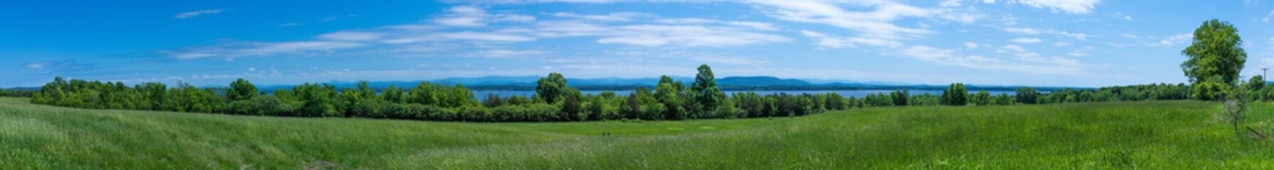 Panoramic view of a land in summer with Lake Champlain and White Mountains in the background