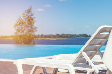 Fototapeta na wymiar Lounge chairs, beach sunbeds in a swimming pool invite you to relax