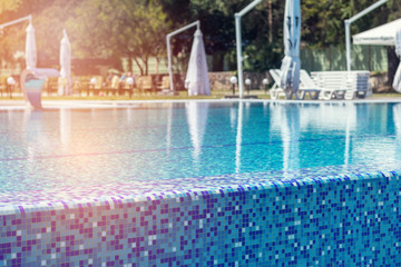 Lounge chairs, beach sunbeds in a swimming pool invite you to relax