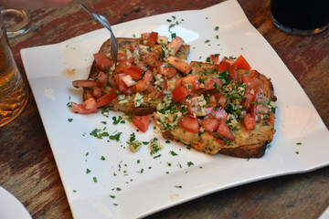 Authentic traditional spanish tapas on a plate. Bruschetta on crusty bread with cheese,tomato,onion and parsley.Food, appetizer. Antipasto in bar.