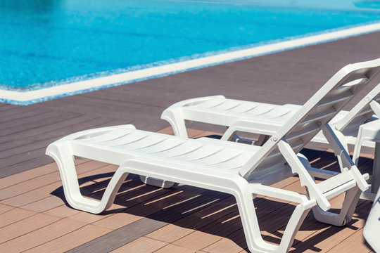 Lounge chairs, beach sunbeds in a swimming pool invite you to relax