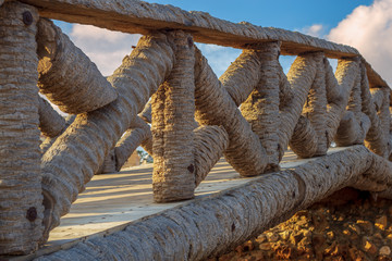 Wooden fence made of palm trunks with partly cloudy sky in sunrise time at Montaza public park in...