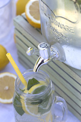 Lemonade in the jug and lemons with mint on the table outdoor