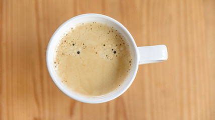 Weiße Tasse mit Kaffee auf Holztisch - Flat Lay