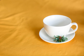 White porcelain teacup and saucer on an orange tablecloth, closeup